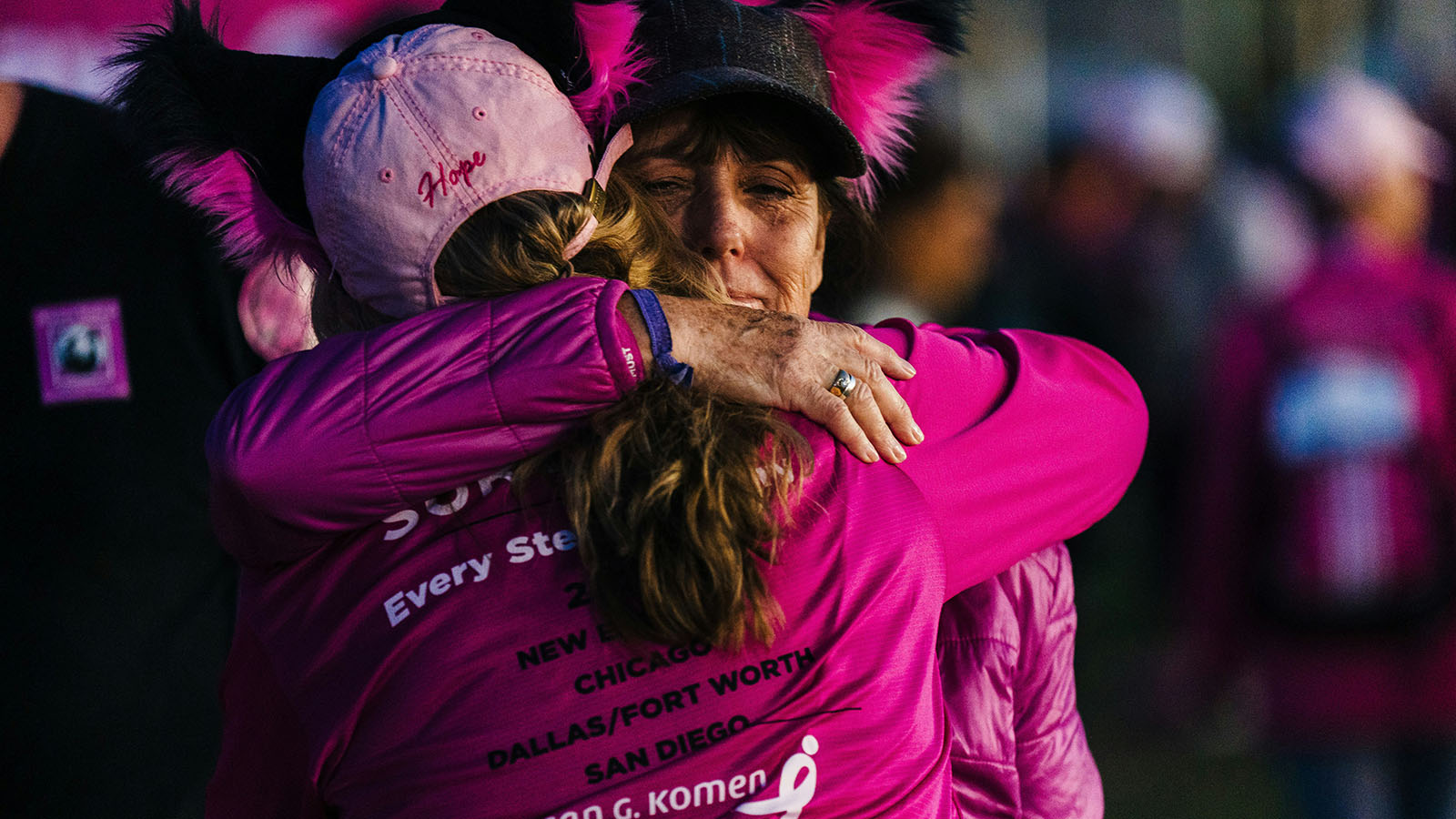 Two participants embracing during a breast cancer awareness fundraising event.