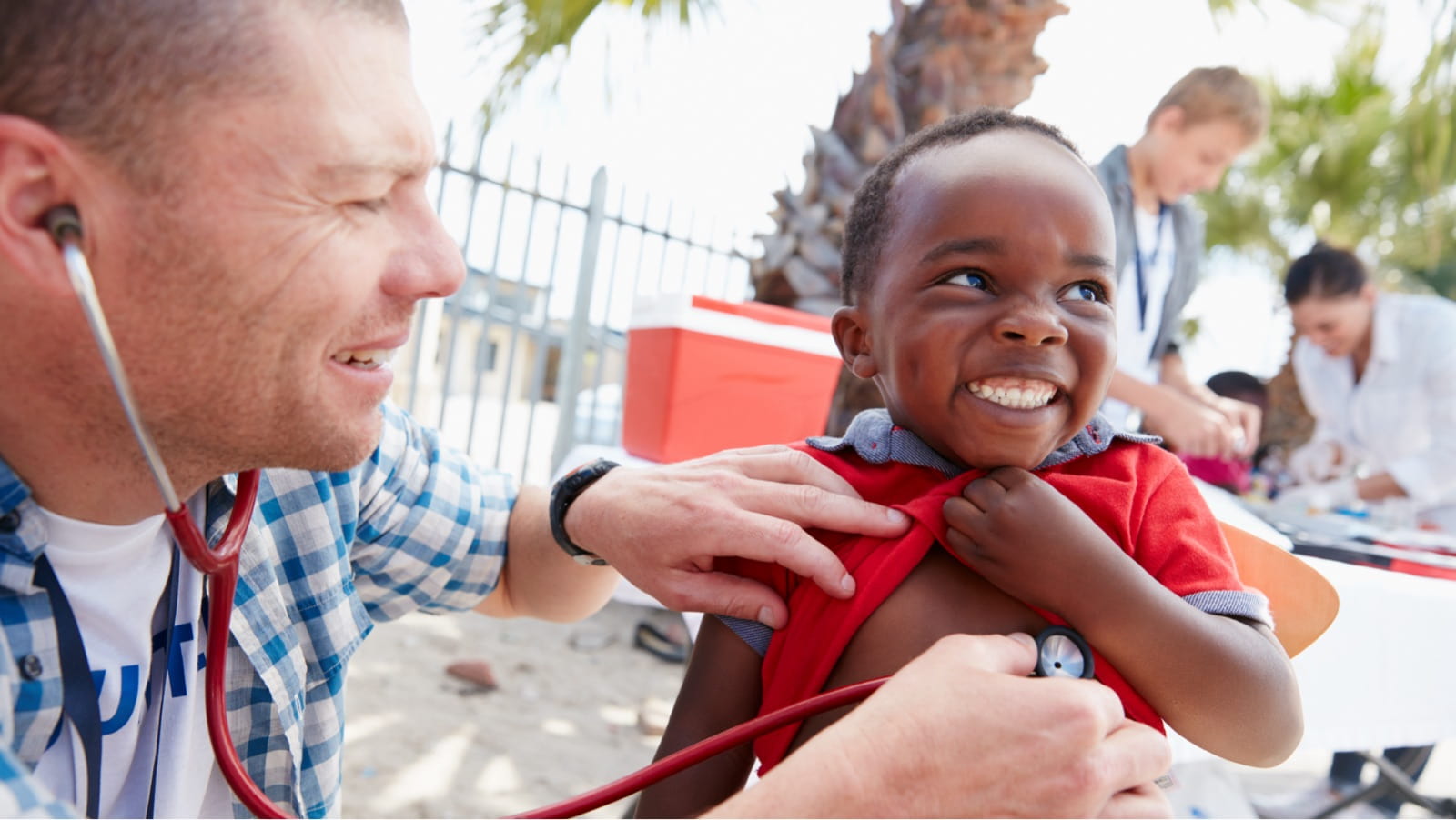 Doctor examines a smiling child using a stethoscope.