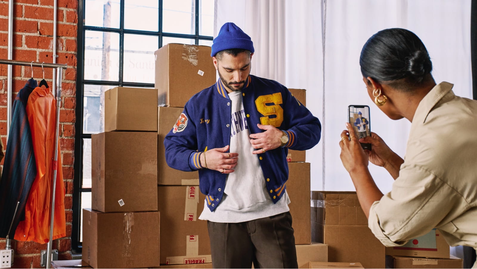 Man modeling streetwear fashion while a woman photographs him.