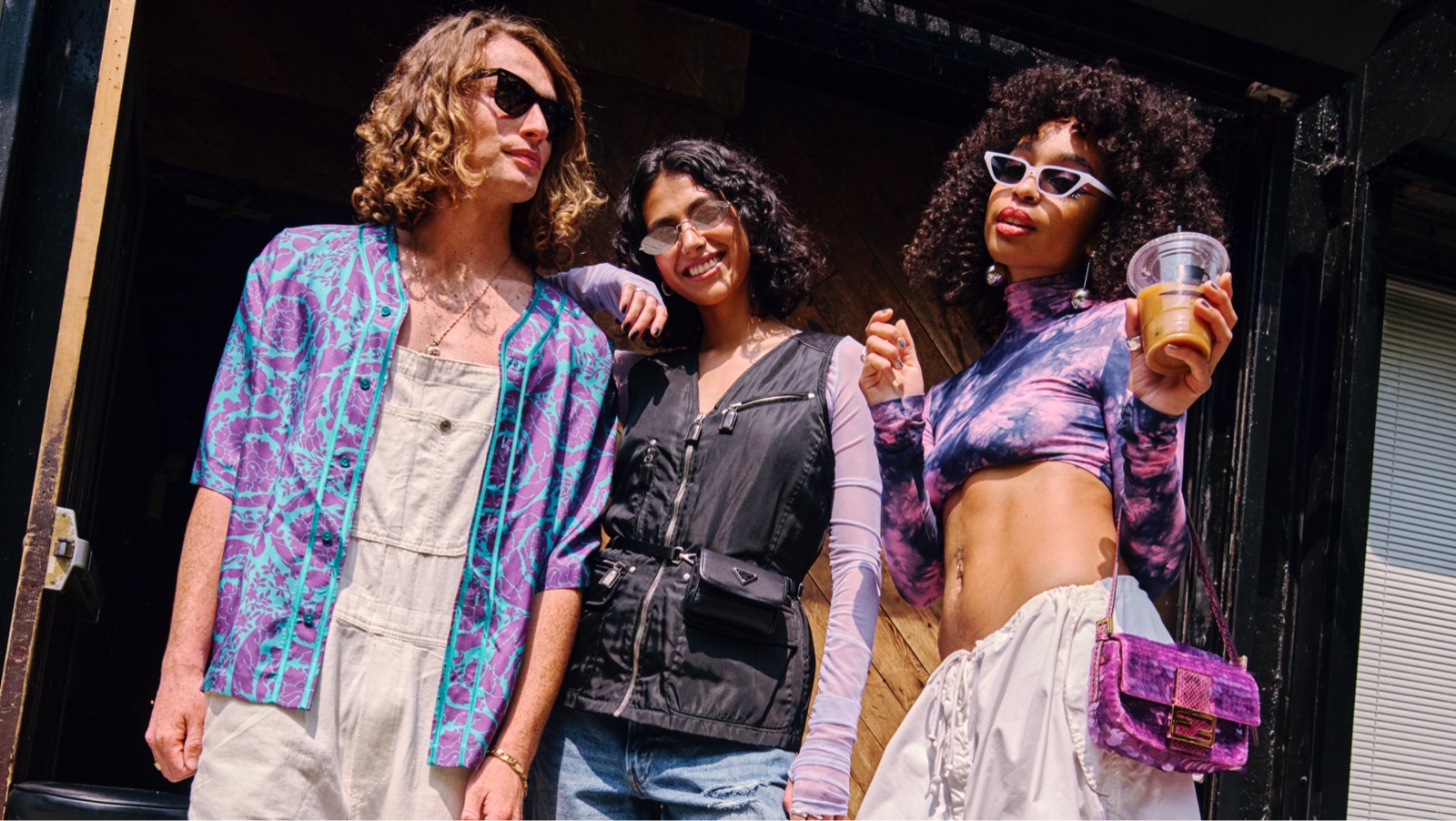 Three people outside in the sunshine smiling and dressed in warm-weather clothing.